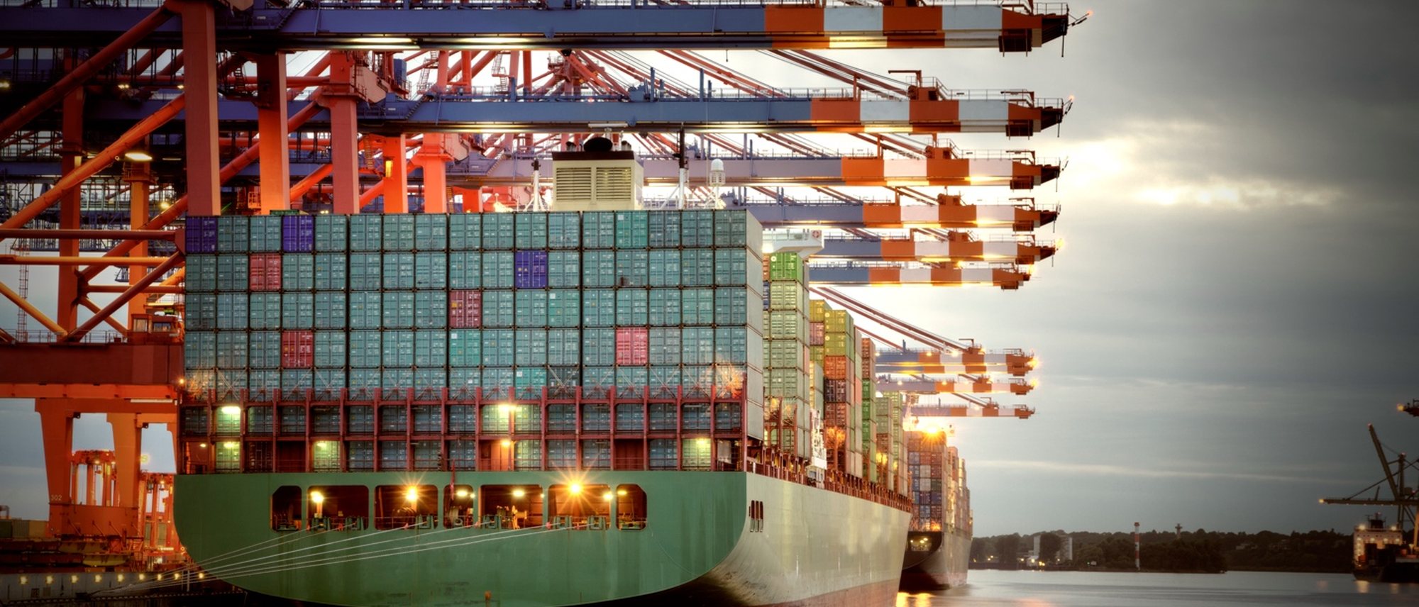 Container ship loading under gantry cranes at dusk